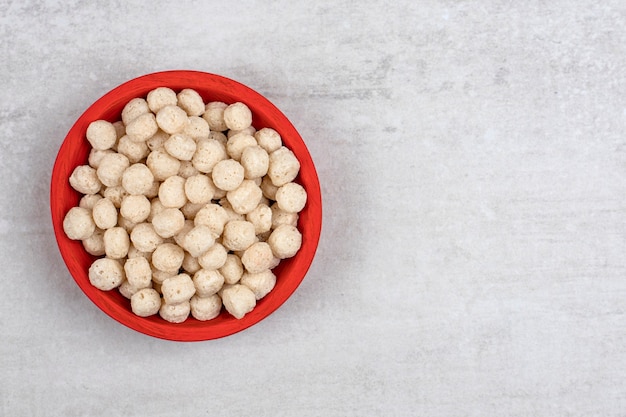 Free photo red bowl full of peeled hazelnuts placed on stone table .