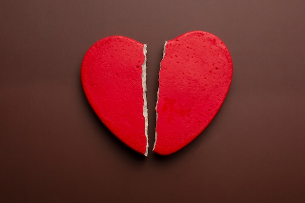 Free photo red broken heart on brown background