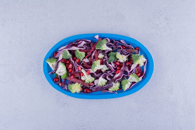 Салат из красной капусты и брокколи, смешанный с гранатовыми листьями на мраморном фоне. Фото высокого качества