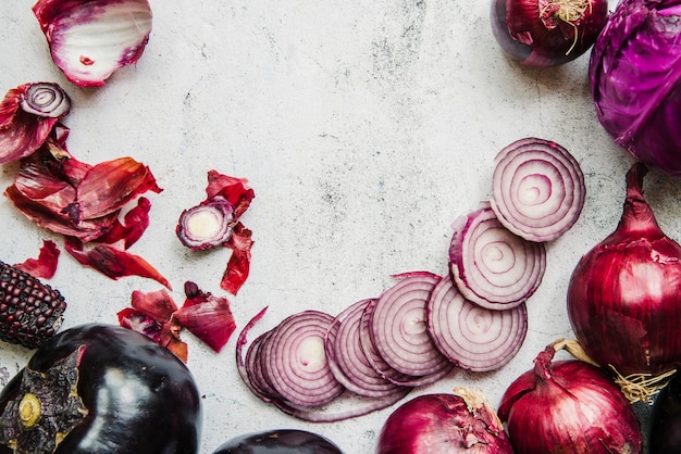 Red cabbage; onions; aubergine and corn cob on textured white backdrop