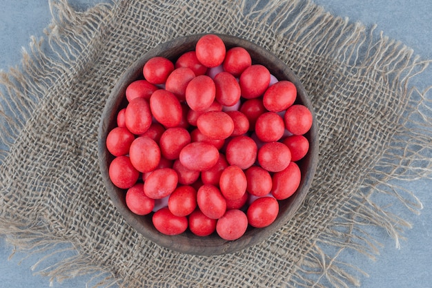 Caramelle rosse nella tazza sul sottopentola, sul tavolo di marmo.