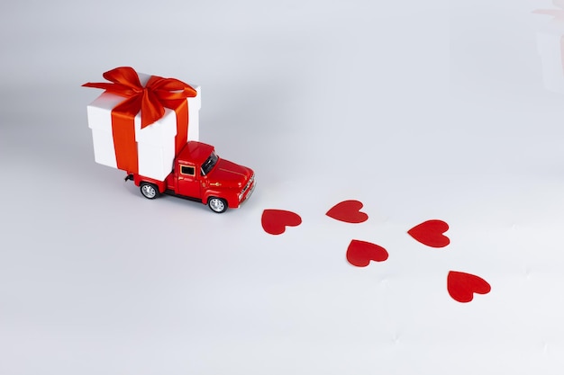 Red car with a gift box on a white background. concept - delivery of gifts for the holidays, valentine's day, international women's day, february 14, march 8. shopping, sale.