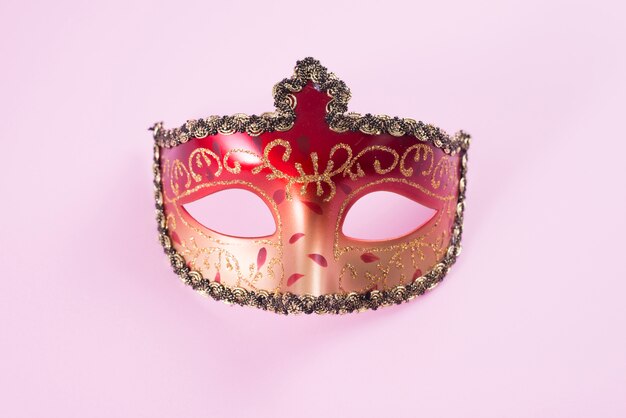 Red carnival mask on pink table