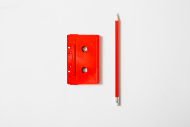 Free photo red cassette tape and pencil on white background