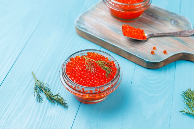 Red caviar in glass bowl and in a spoon, top view