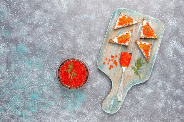 Red caviar in glass bowl and in a spoon, top view