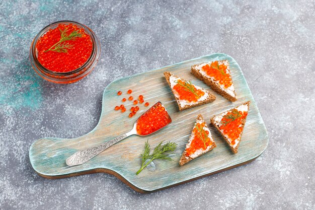 Red caviar in glass bowl and in a spoon, top view