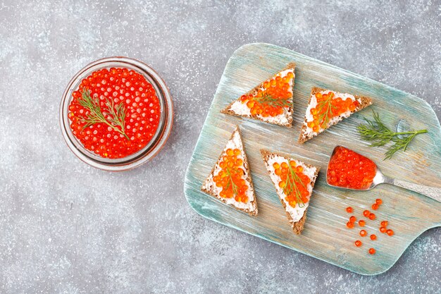 Red caviar in glass bowl and in a spoon, top view