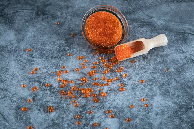 Red caviar in a glass jar on the marble table