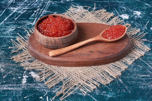 Red caviar on wooden board .