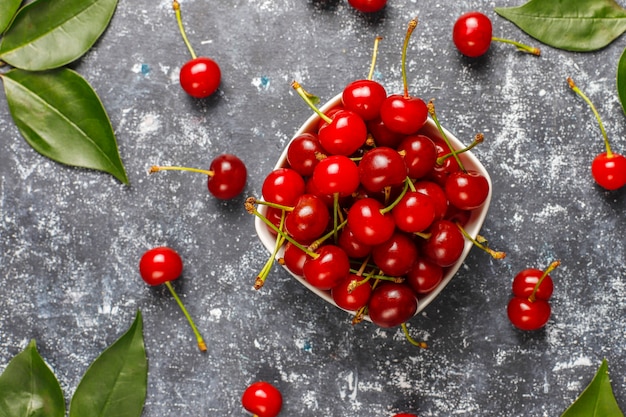 Red cherries in plate bowl on gray table