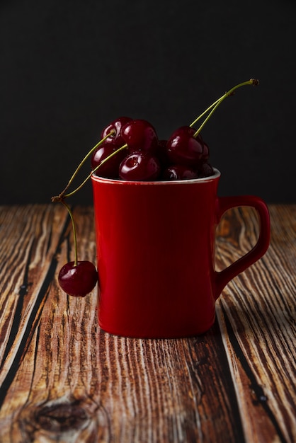 Red cherries in a red cup on the table
