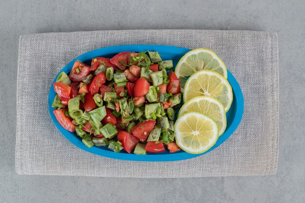 Салат из красных помидоров черри и зеленой фасоли в стеклянных чашках на блюде.