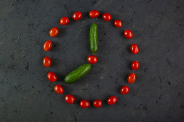 Foto gratuita pomodori ciliegia rossi e cetrioli verdi su fondo scuro