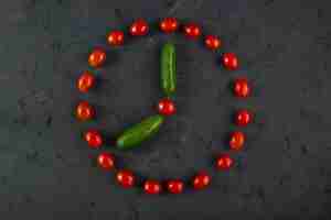Free photo red cherry tomatoes and green cucumbers on dark background