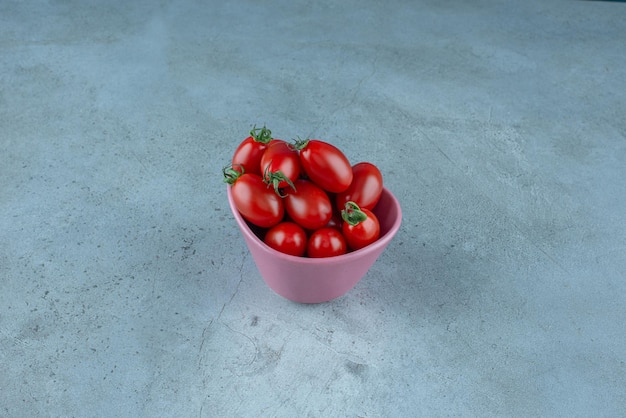 Red cherry tomatoes in a pink cup.