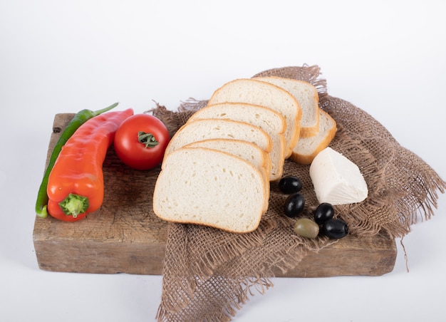 Red chili with tomato, olives, cheese and white bread on a wooden board