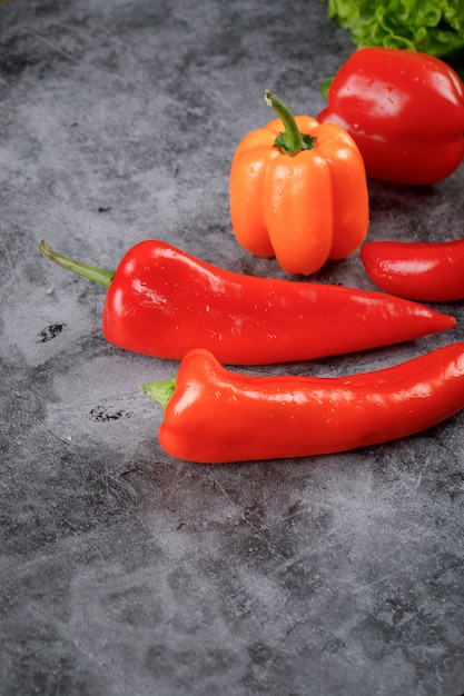 Red chilies and bell peppers on the stone table.