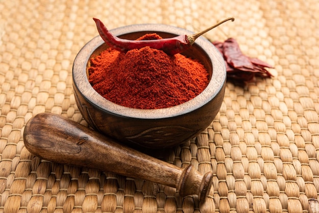 Red chilli or lal mirchi or mirch with powder in a bowl or mortar over moody background, selective focus Free Photo