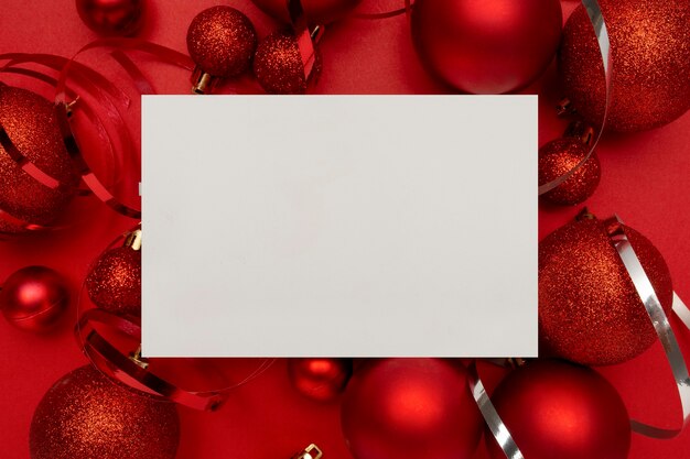 Red Christmas balls and blank card on red table