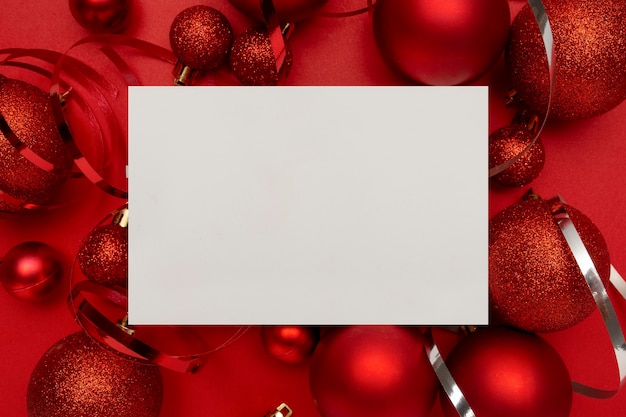 赤いクリスマスボールと赤いテーブルの上の空白のカード
