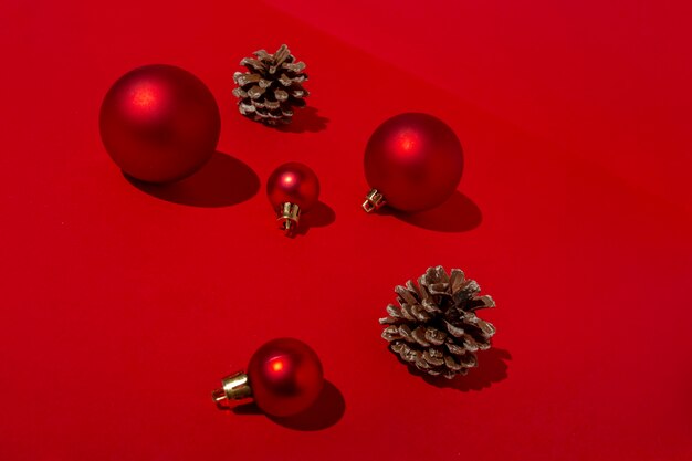 Красные елочные шары и сосновые шишки на красном столе