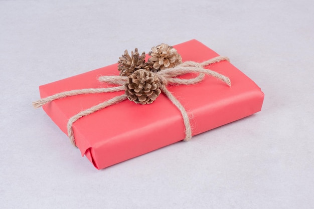 Free photo red christmas box with three pinecones on white table .