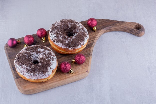 빨간 크리스마스 장식과 흰색 바탕에 나무 보드에 도넛.