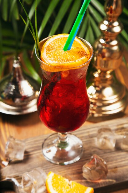 Red cocktail with orange slice on a wooden kitchen table 