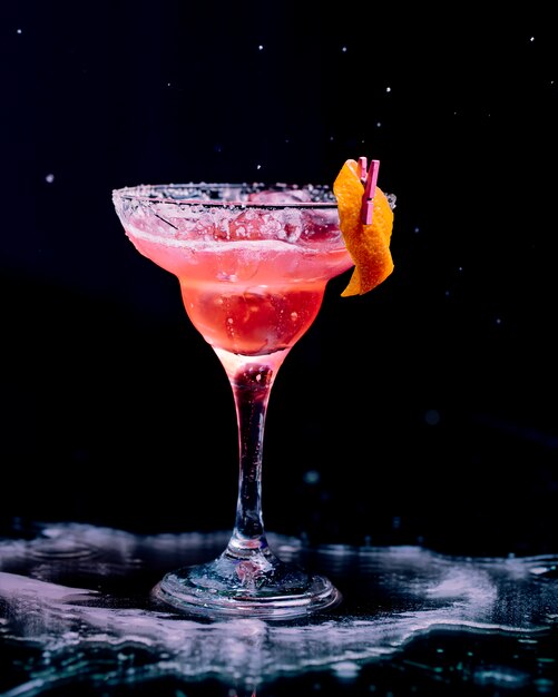 Red cocktail with peeled orange skin and minced ice cubes.