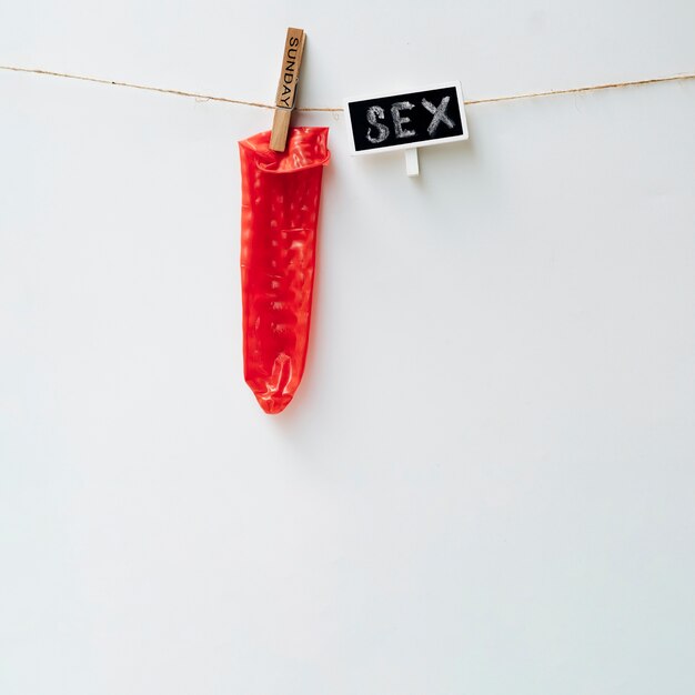 Красный презерватив на бельевой веревке с прищепкой