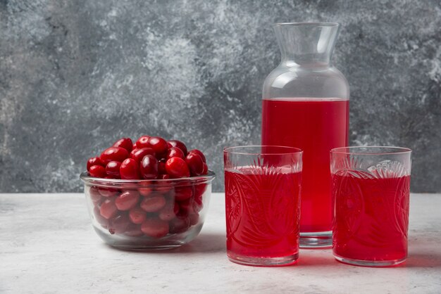 Красные ягоды кизила в стакане с соком в сторону.