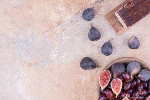 Red cornel berries and purple figs in a wooden platter.