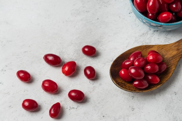 Free photo red cornels in a wooden spoon.