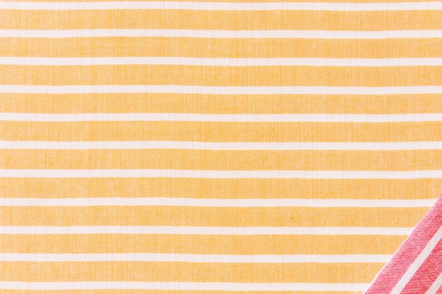 Red corner fabric on yellow and white stripes textile backdrop