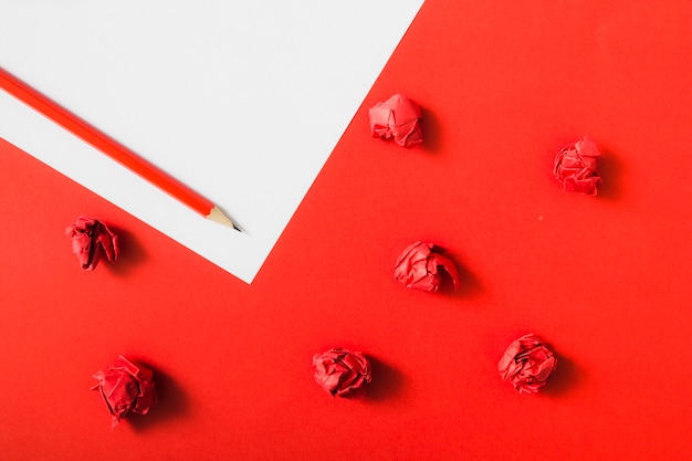 Red crumpled paper on dual paper background with pencil