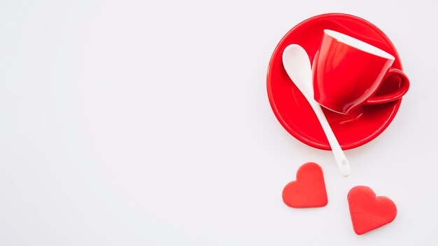 Red cup and dish with spoon near ornament hearts 