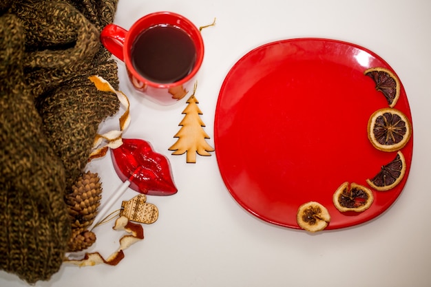 Red cup of tea, plate with dried orange slices and decorative elements