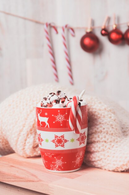 Красная чашка с зефир и конфеты тростями и рождественские шары