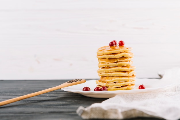 Free photo red currant berries on the stacked of pancakes over the plate
