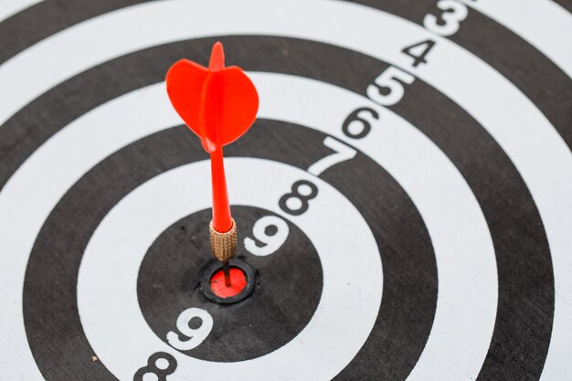 red dart arrow hitting in center of dartboard