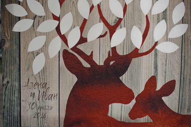 Free photo red deers with white leaves painted on wooden board