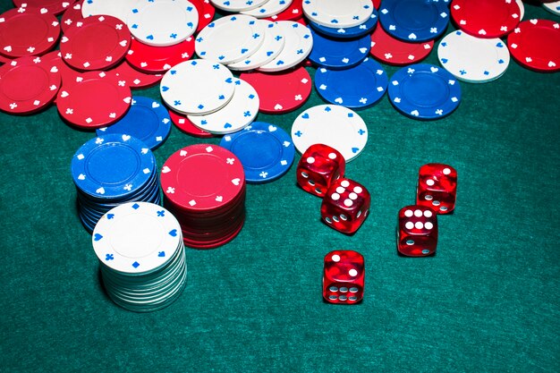 Red dices and casino chips on green poker table