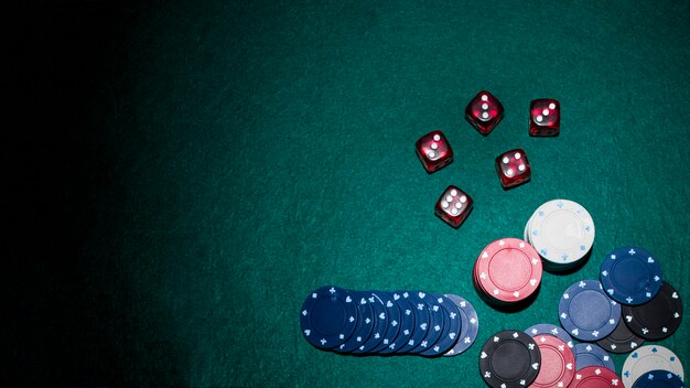 red dices and casino chips on green poker table
