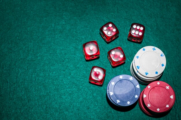 Red dices and casino chips stack on green poker table