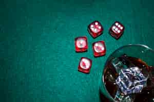 Free photo red dices and whiskey glass with ice cubes on poker table