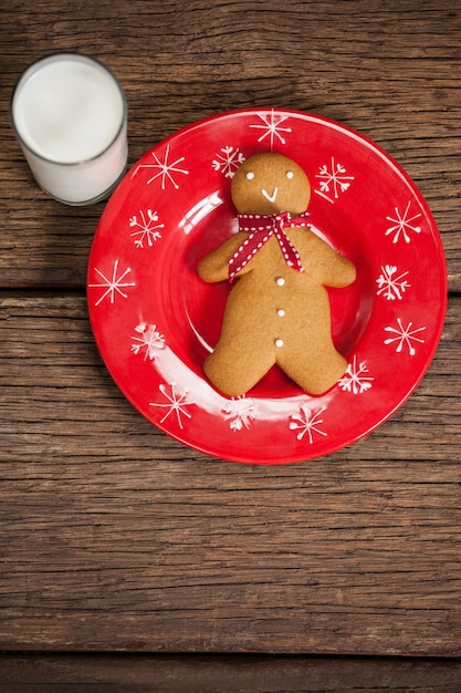 Piatto rosso con i biscotti a forma l'uomo e un bicchiere di latte