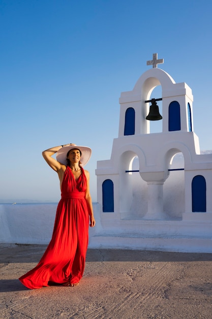 Red dressed woman in oia, santorini, greece.