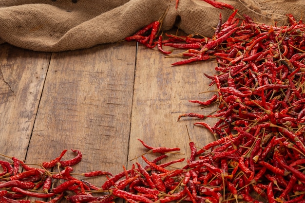 Red dried chilies that are stacked on the plank.