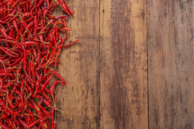 Red dried chilies that are stacked on the plank.